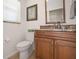 Small bathroom features granite countertop, wood cabinets, and updated toilet at 613 79Th S Cir, St Petersburg, FL 33707