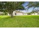 Home's exterior with large oak tree and green lawn at 11609 Weaver Park Ct, Trinity, FL 34655