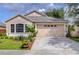 Tan one-story house with a two-car garage and landscaped front yard at 10922 Brucehaven Dr, Riverview, FL 33578