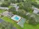 Aerial view showcasing a pool and shuffleboard court nestled among lush green trees and well-maintained residences at 3157 Mission Grove Dr, Palm Harbor, FL 34684