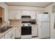 Efficient kitchen with white appliances, painted cabinets and a stainless steel faucet at 3157 Mission Grove Dr, Palm Harbor, FL 34684