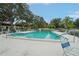 Community pool with lounge chairs, umbrellas, and well-kept landscaping at 3157 Mission Grove Dr, Palm Harbor, FL 34684