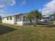Side view of manufactured home with palm trees and grassy yard at 15 Hamilton Ln # 7, Palm Harbor, FL 34684