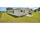Side view of a manufactured home with large windows and grassy yard at 15 Hamilton Ln # 7, Palm Harbor, FL 34684