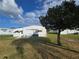 Back view of manufactured home with patio and large tree at 15 Hamilton Ln # 7, Palm Harbor, FL 34684