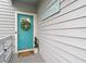 Teal front door with a wreath, welcome mat, and potted plants at 1118 2Nd S Ave, Tierra Verde, FL 33715