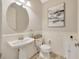 Clean half bathroom features a pedestal sink, toilet, and modern wainscotting and artwork at 16462 Courtyard Loop, Land O Lakes, FL 34638