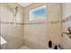 A tiled shower stall with a window and a hand-held shower head gives the stall a luxurious feel at 16462 Courtyard Loop, Land O Lakes, FL 34638