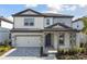 Two-story home with gray siding, stone accents, and a 2-car garage at 1686 Fallon Pass, Zephyrhills, FL 33541