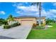 Tan house with 2-car garage, lush landscaping, and palm trees at 2403 Richmond Greens Ct, Sun City Center, FL 33573