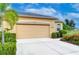 Beige house featuring an attached two-car garage and well-maintained landscaping at 2403 Richmond Greens Ct, Sun City Center, FL 33573