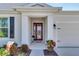 Inviting house exterior featuring a red front door, landscaped entryway, and attached garage at 5607 Limelight Dr, Apollo Beach, FL 33572