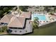 Aerial view of a clubhouse and pool with waterfront access, surrounded by lush landscaping and palm trees at 9495 Blind Pass Rd # 206, St Pete Beach, FL 33706