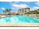 Inviting swimming pool with a brick patio and lounge chairs near lush tropical landscaping and the condo building at 9495 Blind Pass Rd # 206, St Pete Beach, FL 33706