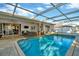Enclosed pool area featuring a bright blue in-ground pool, cage, and outdoor furniture at 13084 Drysdale St, Spring Hill, FL 34609