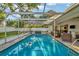 Enclosed pool area featuring a bright blue in-ground pool, cage, and outdoor furniture at 13084 Drysdale St, Spring Hill, FL 34609