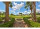 Landscaped walkway leading to a scenic golf course view at 1361 Emerald Dunes, Sun City Center, FL 33573