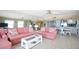 Bright living room featuring pink sofas, a coffee table, light wood floors and a mirrored wall at 19440 Gulf Blvd # 201, Indian Shores, FL 33785