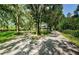 Charming front yard with mature trees and a gravel driveway at 5455 Lake Le Clare Rd, Lutz, FL 33558