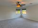 Bedroom with neutral carpet, a ceiling fan, and bright windows overlooking the trees at 7656 Portstewart Dr, Lakewood Ranch, FL 34202