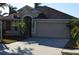 Tan one-story house with dark brown roof, two-car garage, and palm trees at 10718 Standing Stone Dr, Wimauma, FL 33598