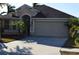 Tan one-story house with dark brown roof, two-car garage, and palm trees at 10718 Standing Stone Dr, Wimauma, FL 33598