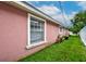 Side view of the home with pink stucco and a window at 6906 N Clark Ave, Tampa, FL 33614