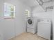 Bright laundry room with a stacked washer/dryer, tile flooring, and natural light from the two windows at 423 Chimney Rock Dr, Ruskin, FL 33570