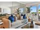 Living area with beige sofa and blue pillows, offering a view of the balcony and ocean at 1120 N Shore Ne Dr # 703, St Petersburg, FL 33701