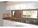 Kitchen featuring white cabinetry, granite countertops, and a stainless steel sink under a large window at 16006 Shinnecock Dr, Odessa, FL 33556