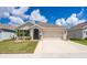 Tan single-story house with a two-car garage, palm trees, and well-manicured lawn at 1523 Glen Grove Loop, Wesley Chapel, FL 33543