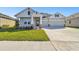 Two-story house with gray siding, stone accents, and a three-car garage at 6179 Hidden Branch Dr, Apollo Beach, FL 33572