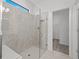 Modern bathroom featuring a glass-enclosed shower with seating and gray tile, adjacent to a doorway with a closet beyond at 2719 Winding Creek Trl, North Port, FL 34289