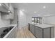 Modern kitchen featuring gray cabinets, stainless steel appliances, island, and an adjacent dining area with sliding glass doors at 2719 Winding Creek Trl, North Port, FL 34289