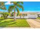 White single-story house with palm trees, driveway, and green lawn at 9125 39Th N Ln, Pinellas Park, FL 33782