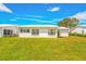 Back of house, featuring a white exterior and expansive green lawn at 9125 39Th N Ln, Pinellas Park, FL 33782