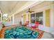 Covered porch with terracotta tile floor, ceiling fan, and two red chairs at 9125 39Th N Ln, Pinellas Park, FL 33782