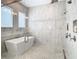 Bathroom with large walk in shower, soaking tub, and marble tile at 8731 Sanders Tree Loop, Wesley Chapel, FL 33545