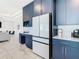 Sleek kitchen with white refrigerator, navy cabinets, and marble-look flooring at 8731 Sanders Tree Loop, Wesley Chapel, FL 33545