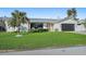 Well-manicured front yard with vibrant green grass, decorative palm tree, modern white home and black garage door at 1367 51St Ne Ave, St Petersburg, FL 33703