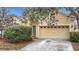 House exterior showcasing light yellow walls, a double-car garage, and landscaping at 10918 Ancient Futures Dr, Tampa, FL 33647