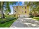 A two-story yellow home with an attached two-car garage, well-manicured lawn, and lush landscaping at 6231 Bayshore Blvd, Tampa, FL 33611