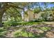 Side view of a yellow three-story home featuring a three-car garage, lush landscaping, and mature trees at 6231 Bayshore Blvd, Tampa, FL 33611