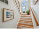 A staircase with hardwood steps, white risers, and a wooden handrail leads to a glass-paneled front door at 6231 Bayshore Blvd, Tampa, FL 33611