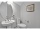 Small bathroom with white pedestal sink, toilet, and oval mirror at 4114 W Zelar St, Tampa, FL 33629