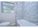 Updated bathroom with marble tile and a classic white bathtub at 1802 E Hamilton Ave, Tampa, FL 33610