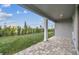 Covered back patio with stone flooring and a view of the green backyard at 6765 Michael Favor Way, Wesley Chapel, FL 33545