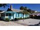 Charming light blue cottage with teal shutters and well-manicured landscaping at 130 E Bay Dr, Treasure Island, FL 33706