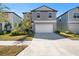 Two-story home with a gray exterior, two-car garage, and landscaping at 9917 Spanish Lime Ct, Riverview, FL 33578