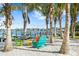 Colorful Adirondack chairs are arranged on a sandy beach under palm trees, near the waterfront at 105 Cordova Ne Blvd, St Petersburg, FL 33704